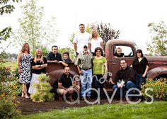 a group of people posing in front of an old truck