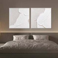 two paintings on the wall above a bed in a room with white sheets and pillows