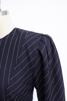 "Vintage 1980s menswear suit inspired dress by Albert Nipon. Cotton blend fabric is navy blue with pin stripes. Gathered shoulder taper with buttons at 3/4 length. High neck. Beautifully seamed bodice rounds to gathering at the side waist. Straight skirt with hidden pockets. Closes with hidden back nylon zip. Lined in nylon save for sleeves. Attached shoulder pads. Label: Albert Nipon Fits like size: Small Measurements: Bust: 34/35\" Waist: 30\" Hip: 36\" Length: 40\" Shoulder: 15\" Sleeve lengt Esprit Clothing 1980s, Vintage Short Sleeve Striped Dress, 1940s Sailor Dress, 1980s Shoulder Pads, Menswear Suit, 1980s Dresses, House Dress, Straight Skirt, Inspired Dress