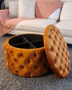 an orange ottoman sitting on top of a carpeted floor next to a white couch