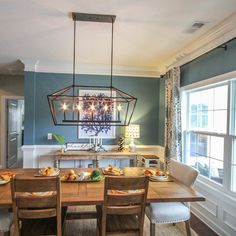 a dining room table with chairs and a chandelier hanging from the ceiling