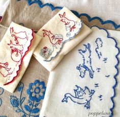 three embroidered napkins on top of each other with blue and red trim around them