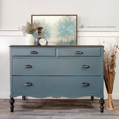 a blue dresser with two vases and a clock on top