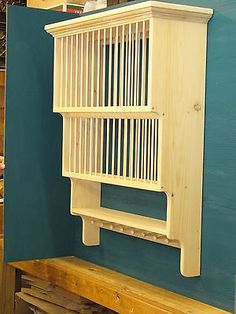 a wooden shelf with a birdcage on it in front of a blue wall