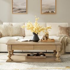 a living room filled with furniture and flowers on top of a coffee table in front of a white couch