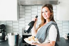 a woman is holding a plate with donuts on it and a blender in the background