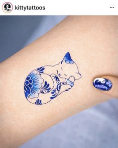 a woman's arm with a blue and white cat tattoo on the left side