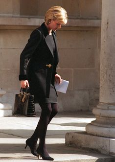 a woman in black is walking down the street