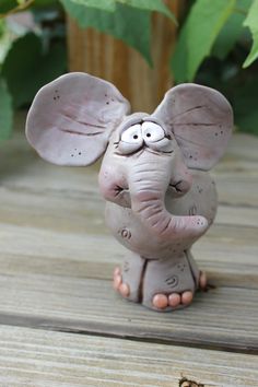 an elephant figurine is sitting on a wooden table next to a potted plant