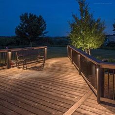 a wooden deck with two benches and lights on it at night in the evening time