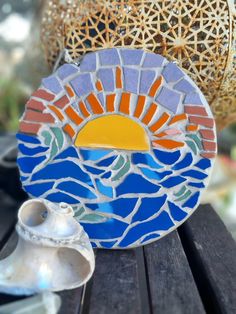 a decorative plate sitting on top of a wooden table next to a vase and seashell