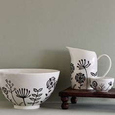 black and white dishes are sitting on a wooden shelf next to a gray painted wall