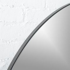 a round mirror on the wall next to a white brick wall