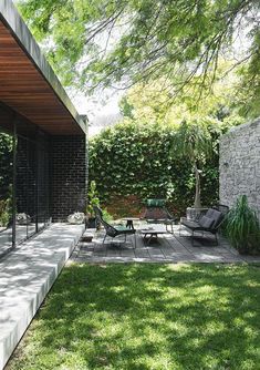 an outdoor patio area with chairs and tables in the grass next to a brick wall