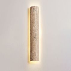 a light that is on the wall next to a white wall with a wooden stick in it