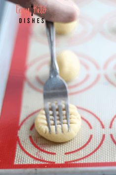 a person is holding a fork over some cookies on a baking sheet with red circles