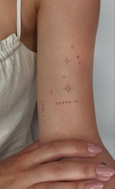 a woman's arm with a small star tattoo on the back of her left arm