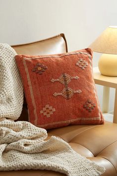 a brown leather couch topped with pillows and blankets