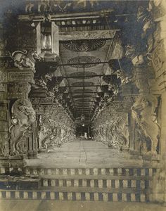 an old black and white photo of a long hallway with sculptures on the walls,