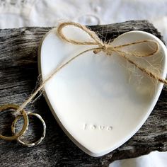 two wedding rings are tied to a heart shaped dish