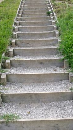 a set of stone steps leading up to the top of a hill with grass growing on both sides