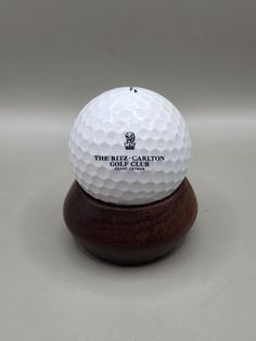 a white golf ball sitting on top of a wooden stand in front of a gray background