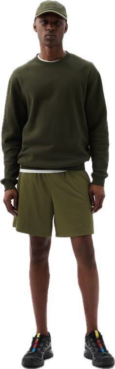 a man in green shorts and a hat standing with his hands on his hipss