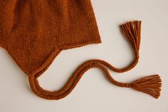 a brown knitted hat with tassels laying on top of it's side