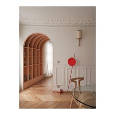 a living room with an arched doorway, table and chair in the corner next to bookshelves