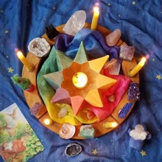 a table topped with candles and rocks on top of a blue cloth