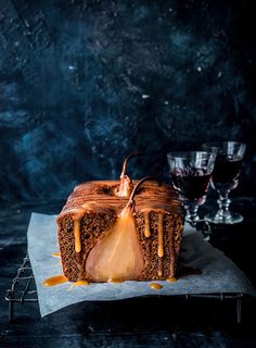 a piece of cake sitting on top of a table next to two glasses and a knife