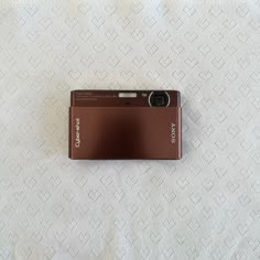 a brown camera sitting on top of a white blanket