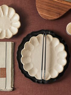 a table topped with plates and bowls filled with food next to utensils on top of a cloth covered table