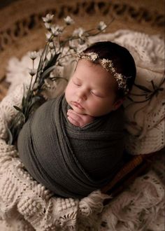 a newborn baby wrapped in a blanket with flowers