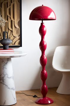 a red lamp sitting on top of a table next to a white chair