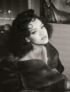 a black and white photo of a woman with curly hair in a fur coat looking off to the side