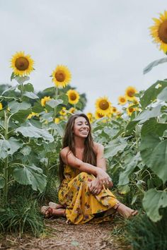 a woman sitting in the middle of a field of sunflowers with her eyes closed