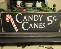 a wooden sign that says candy canes 5 cents on top of a table with christmas decorations