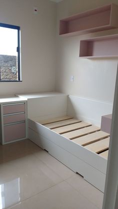 an empty room with a bed, desk and open shelves on the wall next to it