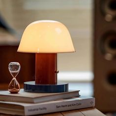 an hourglass sitting on top of a book next to a lamp