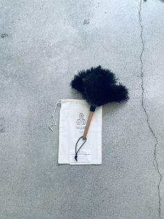 a duster laying on the ground next to a white bag with a black handle