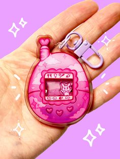 a hand holding a pink clock shaped keychain with scissors in it's palm