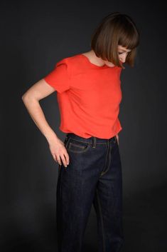 a woman in an orange top is standing with her hands on her hips and looking down