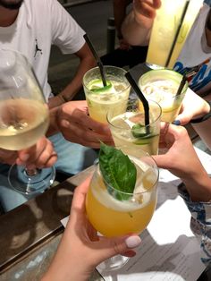 several people holding up glasses with drinks in them