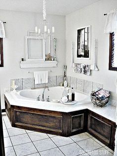 a large white bath tub sitting in a bathroom next to a sink and mirror on the wall