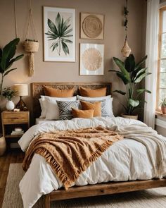 a bed with pillows and blankets on top of it in a bedroom next to two potted plants