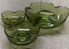 three green glass bowls sitting on top of a gray tablecloth covered floor next to each other