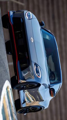 the front end of a silver sports car with its hood up and lights on, seen from above