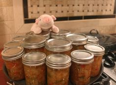 there are many jars with food in them on the stove top and a stuffed animal is next to it