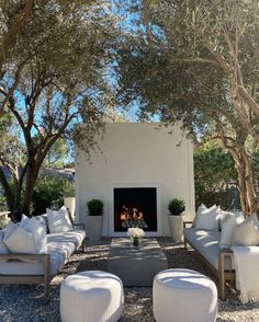 an outdoor living room with white furniture and fireplace